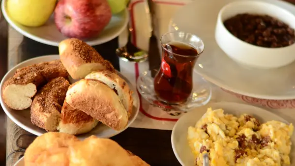 Antikköy kahvaltısında ince belli bardakta demli Türk çayı, taze simit, poğaça ve mevsim meyveleri eşliğinde kahvaltı sunumu.